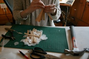 I am threading the wire through the hole to make a cluster of wooden pieces.