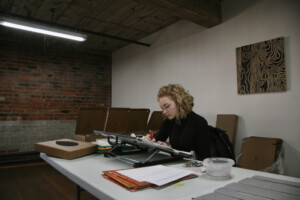 An image of myself carving a lino block with Braille dots.
