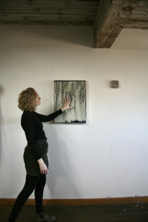 I am touching an artwork that looks like feathers, but is made of Dura-lar pieces stuck onto a canvas with oil paint.
