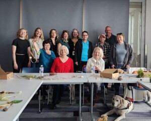 A group of 12 people and a seeing eye dog taking a group picture together.