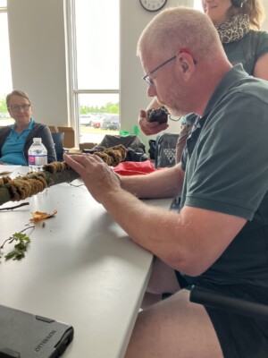 A man is feeling the texture of soft fungus layers attached to a large branch.