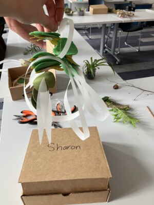 A finished mobile sculpture with many loops and layered felt pieces that resemble leaves in between.