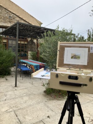 My pochade box set up on a tripod with a painting in progress of the dining area in the backyard garden.