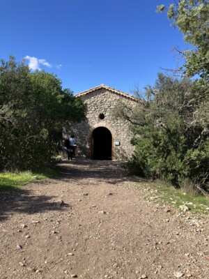A path leads up to a small chapel with trees on either side.