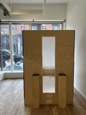 A front view of the booth structure with diffused light through the central window and a plinth on either side. The large windows behind wrap around the background.