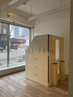 A side view of the booth structure with bright light streaming in through the large windows behind, creating a warm glow on the wooden surface.